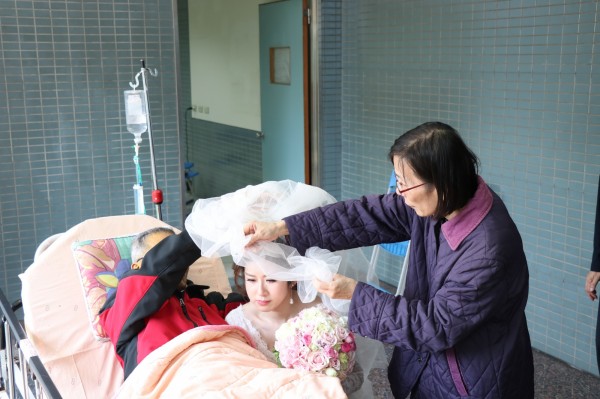 侯啟雄(左)、邱秀珍(右)一同為愛女侯宛君蓋上頭紗。(記者王善嬿翻攝)