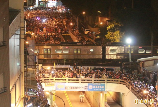 大甲媽祖鑾轎來到民生地下道,陸橋上的火車也突然停下,彷彿也要看「搶轎」好戲。(記者陳冠備攝)