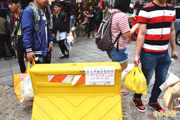 中平商圈車阻器被偷1年,路口的注水式塑膠護欄形同虛設,汽機車想闖就闖,行人必須邊逛邊閃車,險象環生。(記者李容萍攝)