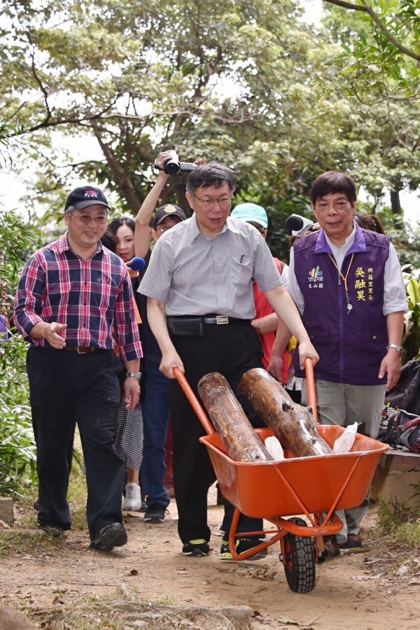 柯文哲今天上午與文山社區大學、千里步道協會一起到文山區中埔山步道搬著石頭、推著木頭，體驗打造手作步道的樂趣。（市府提供）