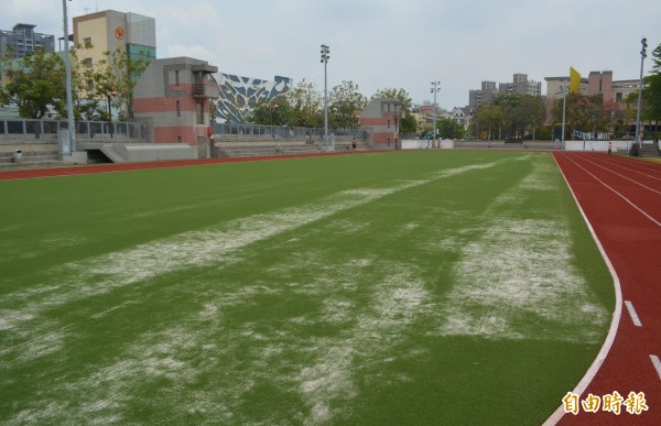 大里運動公園新啟用的田徑場，人工草皮上布滿分布不均勻的石英砂。（記者陳建志攝）