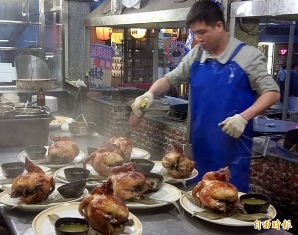 溪頭妖怪村「蝴蝶雞」出爐上桌前，還噴上獨門醬料讓烤雞退火鎖住肉汁情形。（記者謝介裕攝）