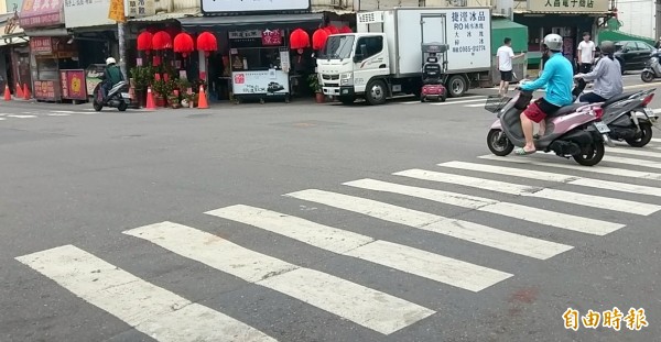 南投市王姓男子駕駛醫療電動代步車「貼著」貨車奇景，引發往來民眾關注的目光。（記者謝介裕攝）