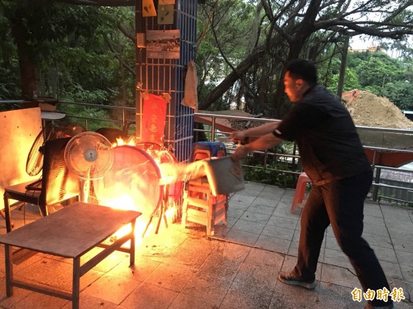 基隆市中正公園主普壇旁鄉親亭內2張紅色塑膠椅起火燃燒。路過林姓民眾見義勇為，提涼亭旁水桶滅火。（記者林嘉東攝）