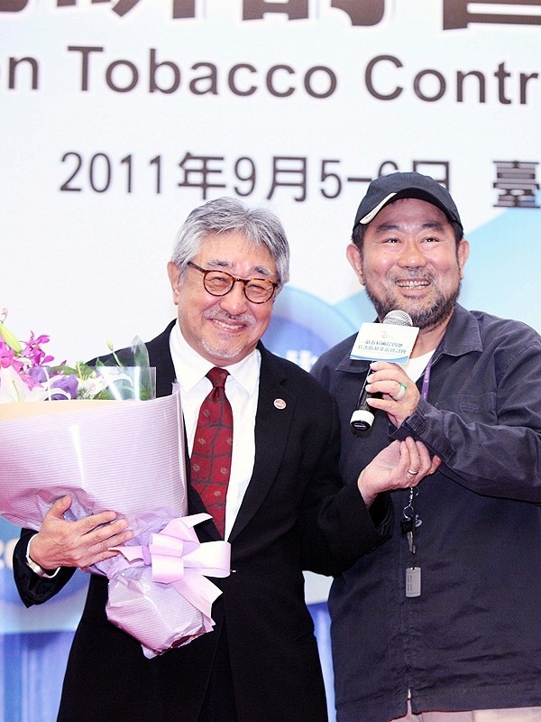 2011年,第5屆兩岸四地菸害防治交流研討會,已故藝人趙舜(右)上台獻花。(圖由董氏基金會提供)