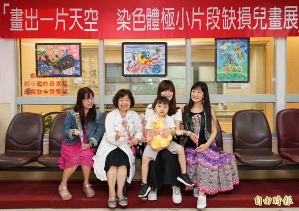 將滿7歲的陳柏丞由母親梁嘉妮抱著出席彰基兒童醫院畫展,讓大家分享他一幅幅的美麗畫作。。(記者湯世名攝)