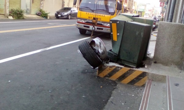 小客車右前輪卡在變電箱上，讓圍觀民眾直呼離奇。（記者張勳騰翻攝）