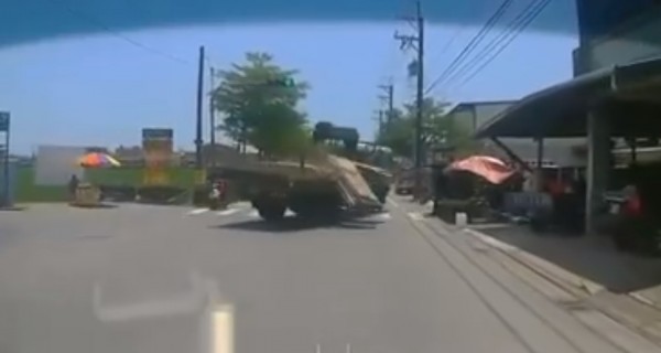 一輛滿載灌漿模板的大貨車,行經宜蘭縣礁溪鄉育龍路時,疑貪快甩尾過彎,車上木板四散,險砸毀一旁水果攤。(圖擷取自「爆料公社」)