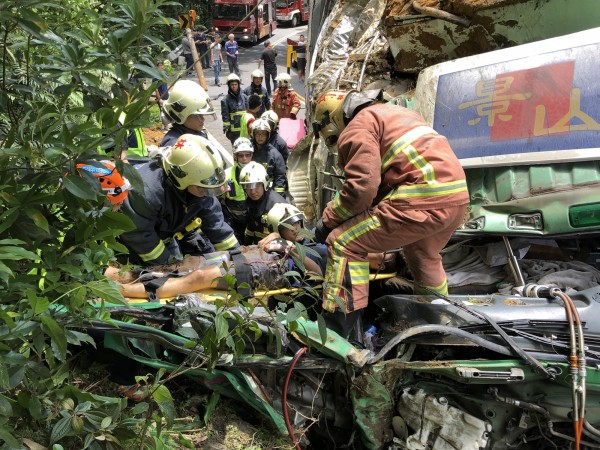 大貨車於北宜公路55.7K處自撞山壁，副駕駛座乘客卡在車內，警消動用機具將人救出。（記者陳薏云翻攝）