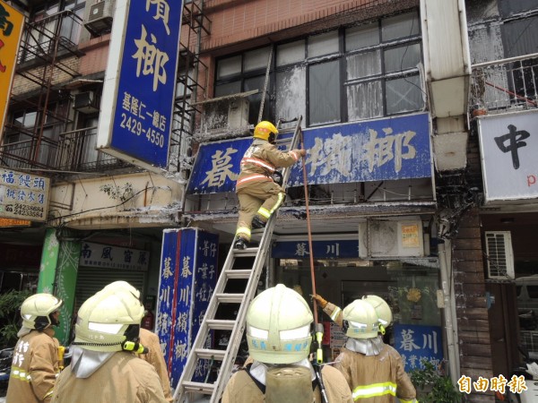 基隆市仁愛區暮川檳榔廣告看板中午疑似電線短路悶燒，消防隊員出動迅速撲滅火勢。（記者林嘉東攝）