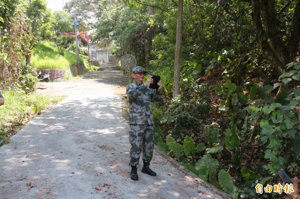 魏明仁身穿解放軍服，站在警方後方20公尺，開手機直播抗議過程。（記者陳冠備攝）