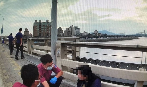 警消趕扺發現38歲何女坐在橋上人行道,士林警方和消防救護人員輪番上陣勸說。(警方提供)