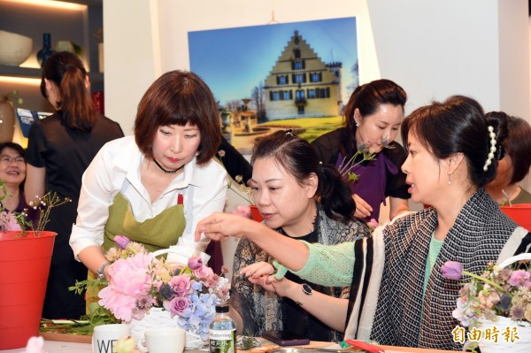 美國芝加哥花藝學校花藝講師吳慧萍（左一），指導學員用黏貼及堆疊的技巧，一牽一引下，將女性內斂溫潤的情韻，透過具象的花藝來呈現。（記者張忠義攝）