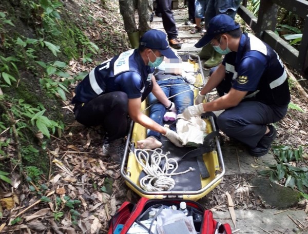 消防隊員將遭落石砸傷遊客固定在擔架上。(記者蔡宗勳翻攝)