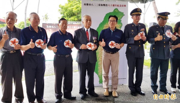 老英雄手持代表高雄的木棉花，與高雄市民政局長張乃千（左五）一起放在台灣地圖，象徵守護台灣。（記者陳文嬋攝）