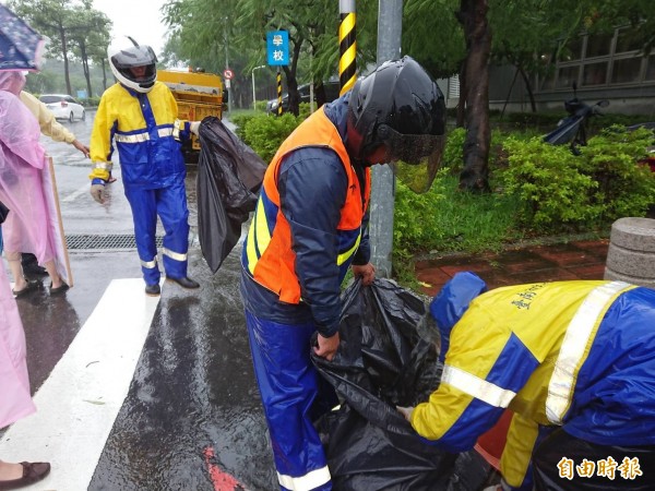 清潔人員冒雨加強清理道路側溝落葉防阻塞。（記者洪瑞琴攝）