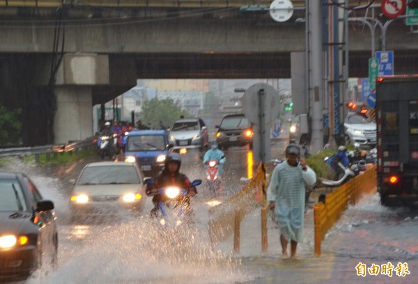 台南雨勢不斷，中山高仁德交流道下方積水未退，人車涉水而過。（記者吳俊鋒攝）