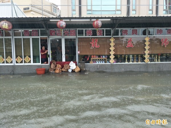 居民堆沙包防止水淹進店內。（記者邱灝唐攝）