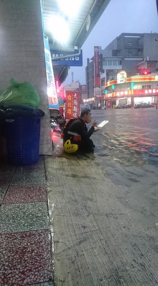 大灣消防分隊隊員林佳嶸在大雨中吃著便當，被拍下PO在臉書《台南諸事會社》，這一幕讓許多網友相當感動。（記者萬于甄翻攝）