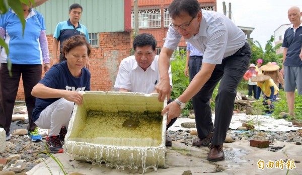 南投縣衛生局長黃昭郎、副縣長陳正昇及南投市長宋懐琳（右至左），對軍功社區居民示範清除積水情形。（記者謝介裕攝）