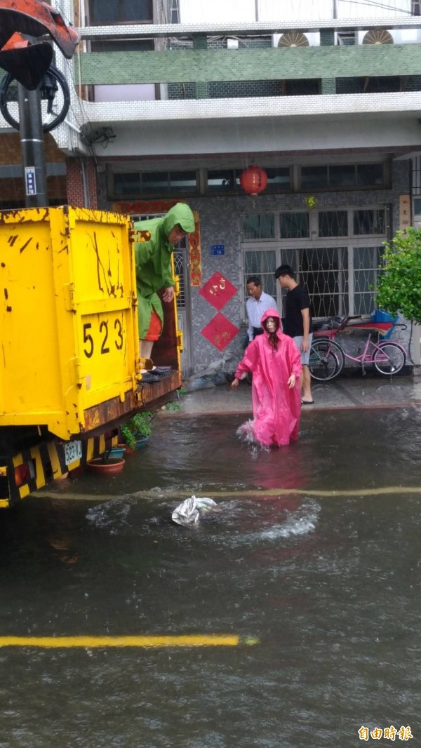 南州萬華村水患依舊，鄉代劉美吟幫忙搬沙包給居民擋水。（記者陳彥廷攝）