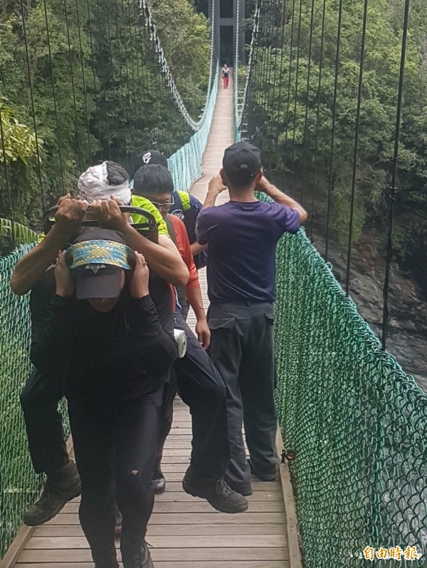 受傷的陳男伏坐在山青的鋁背架上，慢慢被背負下山。（花蓮縣消防局提供）