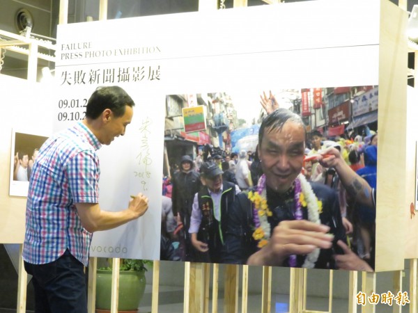 新北市長朱立倫在潑水節被潑得全身濕、狼狽不已的照片,獲得失敗新聞攝影展的第一名,朱立倫出席展覽並在照片旁簽名。(記者何玉華攝)