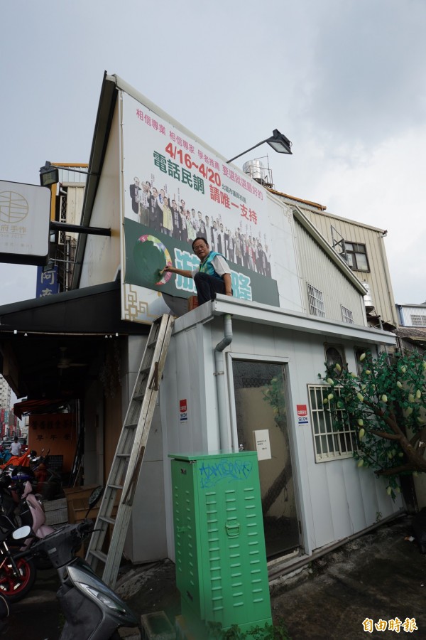 北區議員參選人游金隆登高擦油漆塗銷自己競選看板上的黨徽等政黨記號。（記者蔡淑媛攝）                                 