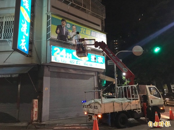 北區議員參選人游金隆登吊車擦油漆塗銷競選看板上的黨徽記號，並開直播見證。（記者蔡淑媛攝）          