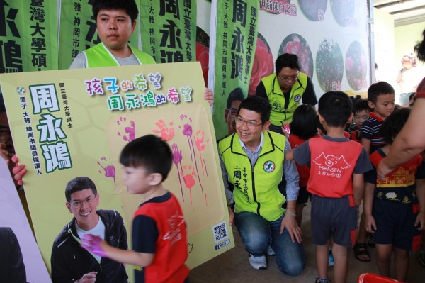 小朋友在看板上蓋下手印，象徵參選人和孩子「心手相連」，承諾創造出讓他們快樂成長的優良環境。（周永鴻提供）