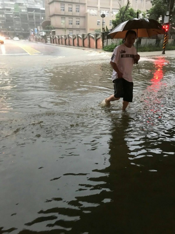 基隆市今早大雨再下，獅球路成功國小大門前積水，市民仍涉水而過。（記者俞肇福翻攝）