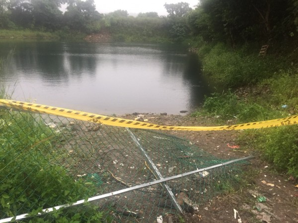 大溪警方在石園農場荒廢釣魚池發生溺水案後，在魚池拉起警戒線，而一旁就是被破壞倒地的塑膠網。（記者李容萍翻攝）