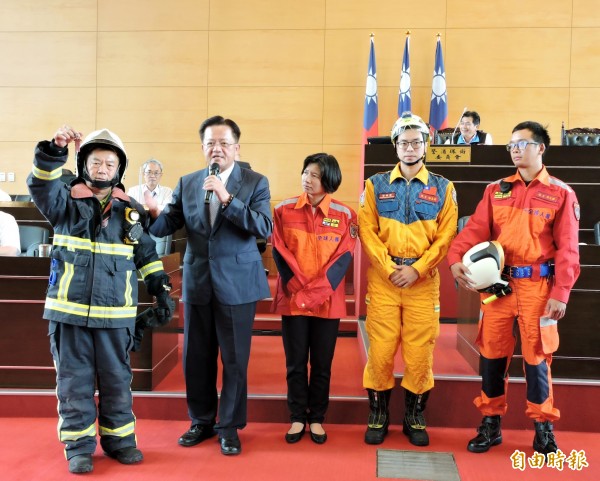 市議員鄭功進(左1)穿上消防衣,並請副市長林依瑩換上(左3)的救助服,由消防局長蕭煥章(左2)說明兩者的用途。(記者張菁雅攝)