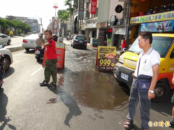 機車行師傅在場協助指揮人車慢行通過油漬區路面。（記者王俊忠攝）