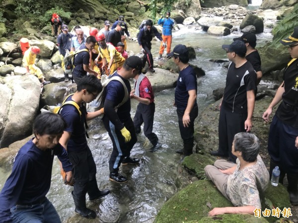 徐姓妻子坐在溪邊，身體健況無大礙。（記者鄭名翔攝）