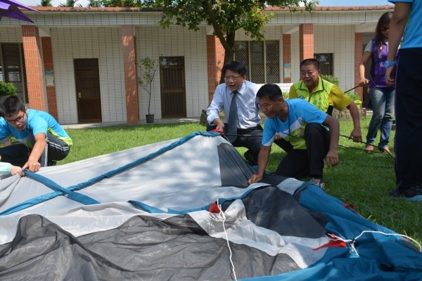 崙川露營區今天開幕，屏東縣長潘孟安（左二）前往鼓勵工作人員，還一同搭帳篷。（圖由屏東縣政府提供）