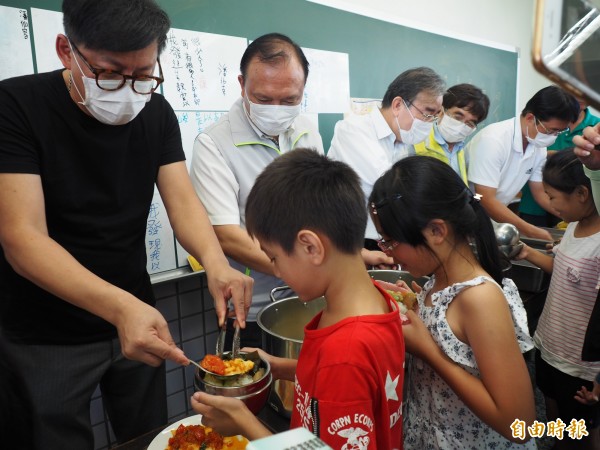 型男主廚詹姆士（後排左一）與農委會主委林聰（後排左二）賢當起打菜幫手，為小朋友的午餐添菜。（記者王秀亭攝）