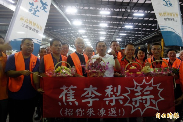 國民黨新北市長參選人侯友宜今早到三重果菜運銷市場拜票，市場改建委員會熱情送上香蕉、李子、水梨、蒜，祝福侯友宜「招你來凍選」。（記者葉冠妤攝）