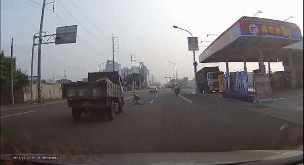 一輛貨車行駛在內線車道，經過加油站時，一名男子突然從路旁衝出，看到了貨車就「匍匐臥地」，疑似想製造假車禍，幸貨車及時煞停。（翻攝自爆料公社）