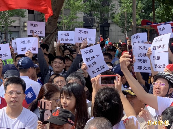 抗議人士高舉抗議標語。(記者許倬勛攝)