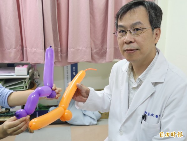 豐原醫院泌尿外科醫師郭嘉政以氣球比擬,橘色為正常陰莖、紫色則因陰莖骨折,致血腫發紫且拗折如薩克斯風狀。(記者歐素美攝)