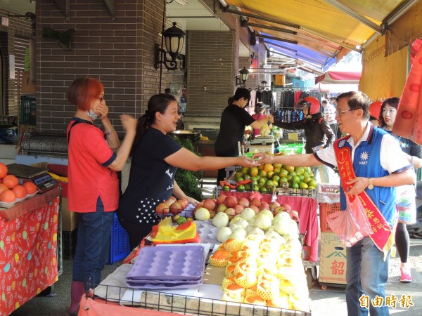 国民党南投县长候选人林明溱(右)到菜市场扫街,向民众问候博感情。(记者刘滨铨摄)