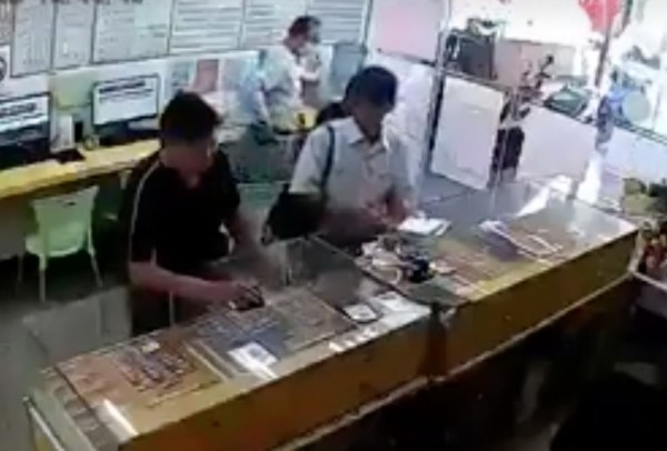 「彩劵大盜」鄭添貴頭戴鴨舌帽(前右)手拿白色彩券左顧右盼。(翻攝畫面)