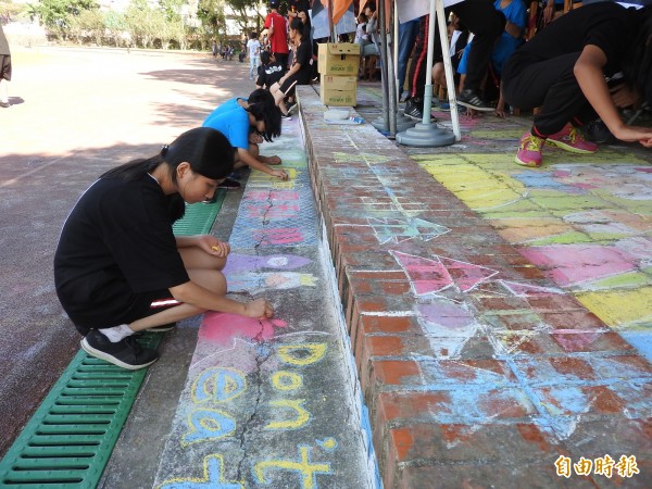 宏仁國中同學利用校慶前1天的課餘時間進行粉筆彩繪校園。（記者佟振國攝）