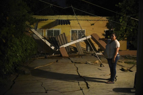 民眾指著自家屋頂，在地震中嚴重受損。（歐新社）
