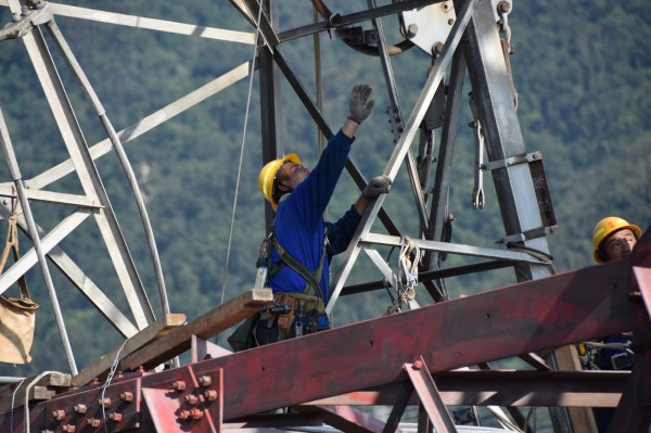 搶修工人頂著大太陽攀塔進行鐵塔組立工作,雖然悶熱難耐,但為了安全還是必須穿著長袖長褲。(經濟部提供)