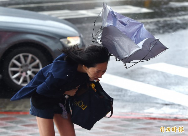 東北風與輕颱卡努產生共伴效應,中央氣象局13日發布8縣市大雨及豪雨特報,包括宜蘭、台北市部分地區上午累積雨量都已破百毫米,市區吹起強風並下起大雨,讓街頭行人吃足苦頭。(記者廖振輝攝)