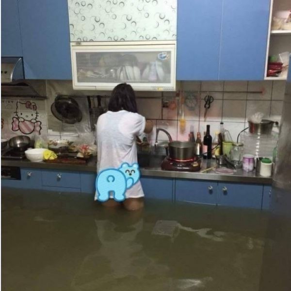 台南麻豆一名媽媽在淹大水的廚房煮飯，她表示家裡有2名小孩，因為淹水嚴重而無法外出，但又不能讓小孩餓肚子，只好克難地煮飯給他們吃。（圖擷自臉書「爆料公社」）