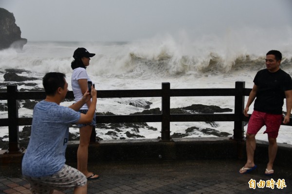 強颱「山竹」從鵝鑾鼻南方海域經過，掀起恆春半島巨浪風雨，許多「勇敢」中客無懼風雨，好奇到海邊搶拍紀念照。（記者蔡宗憲攝）