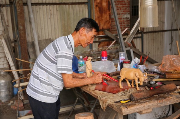 李養不僅製作竹籠厝，閒暇之餘也跟兒子合力製作農村的人物和農具模型。（記者潘自強攝）